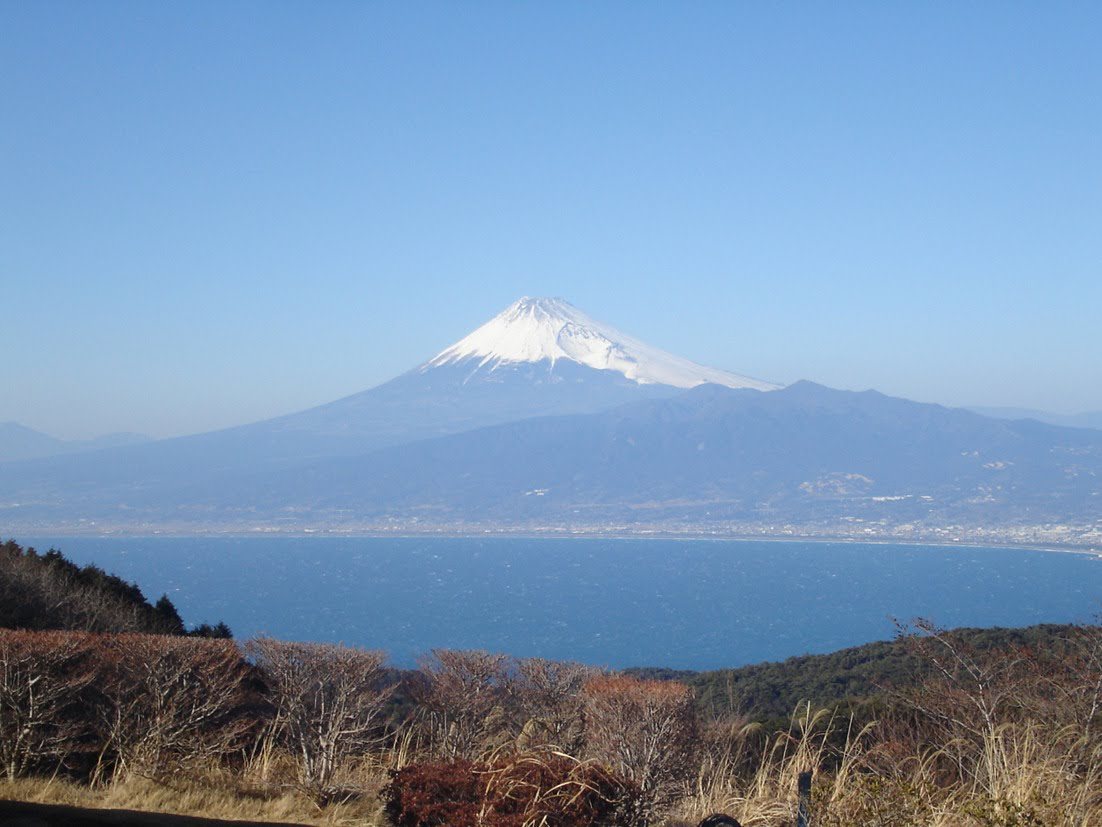 Mount Fuji seen across the water from the hills of Izu, snow on the summit