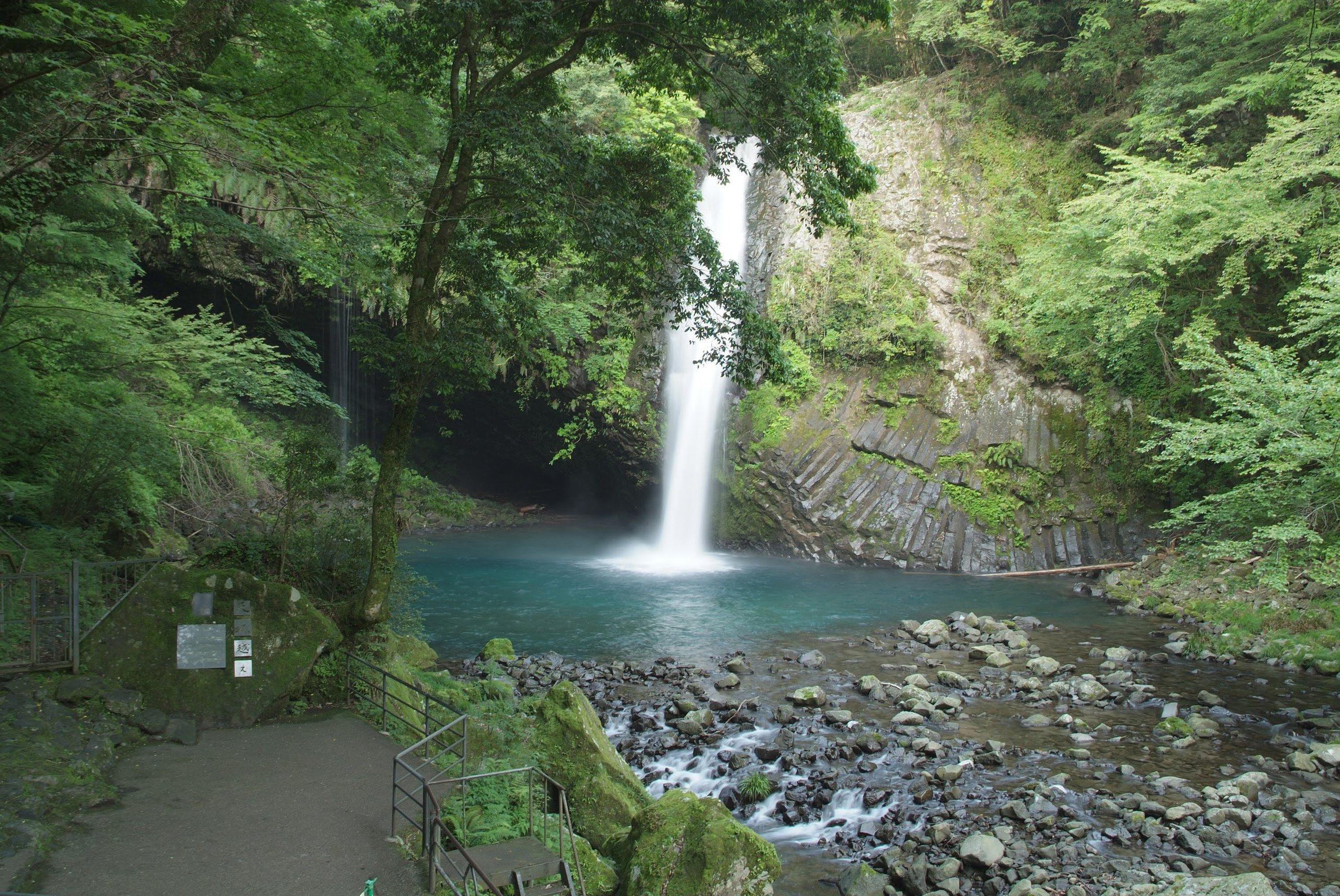 A waterfall in the Amagi valley falling into a clear green pool beneath a columnar rock face