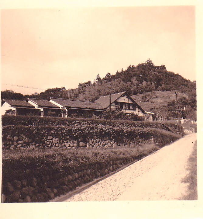 Shirakabe photographed from the road in its founding years, the inn set above a stone retaining wall in Yugashima