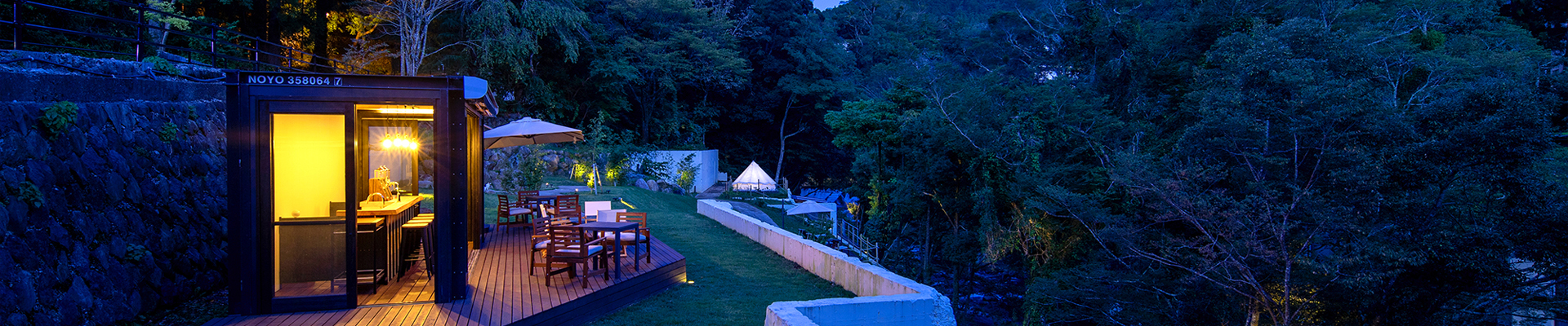 The riverside terrace at Shirakabe glowing above the forest after dark