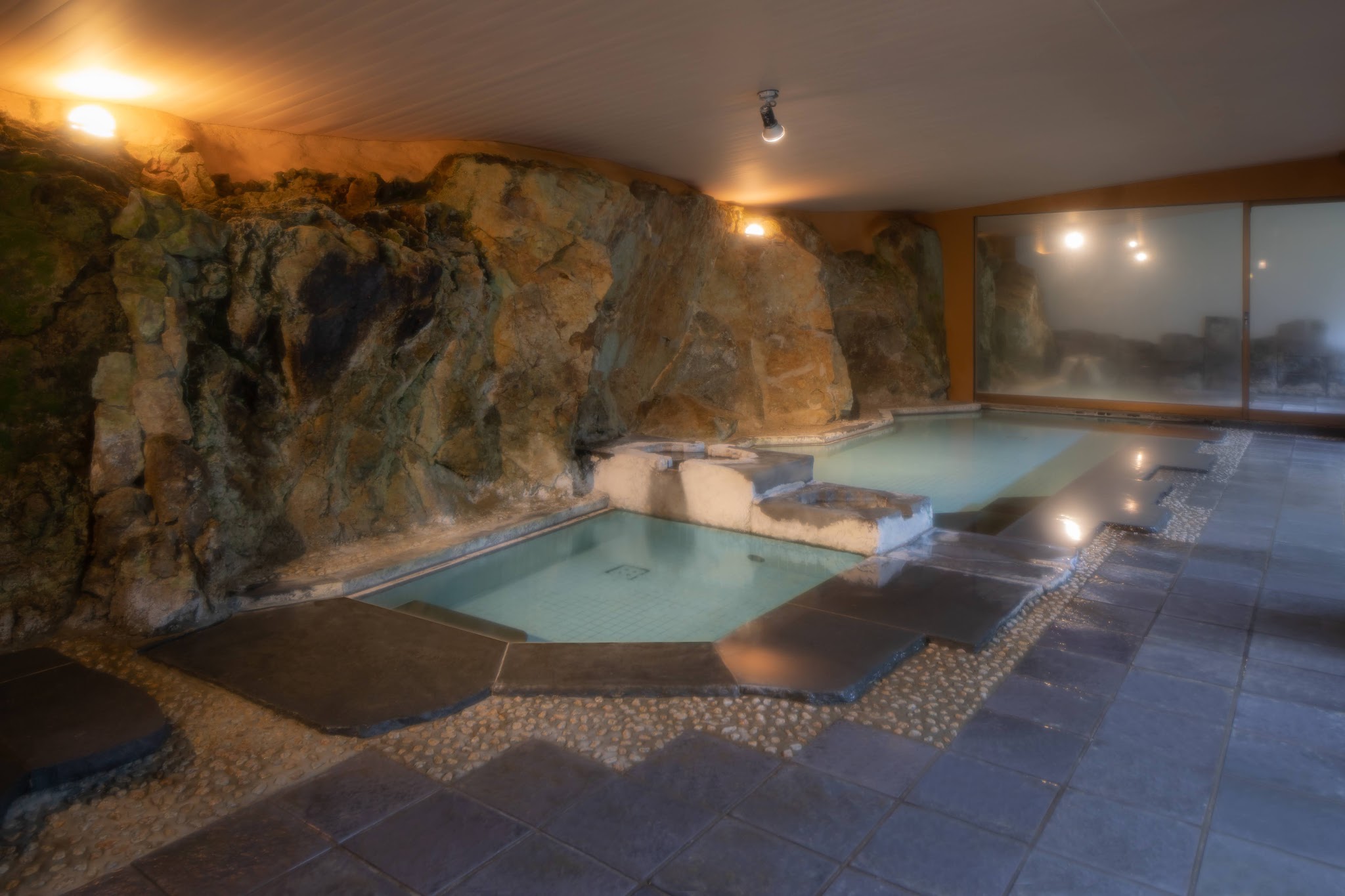 The great bath at Shirakabe, its rock face formed from the ejecta of ancient submarine volcanoes, the spring water still and steaming